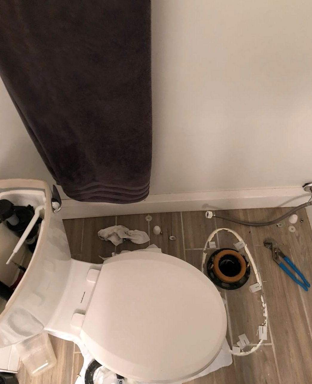 Toilet lifted off its flange with a new wax ring on the closet flange and tools on the floor