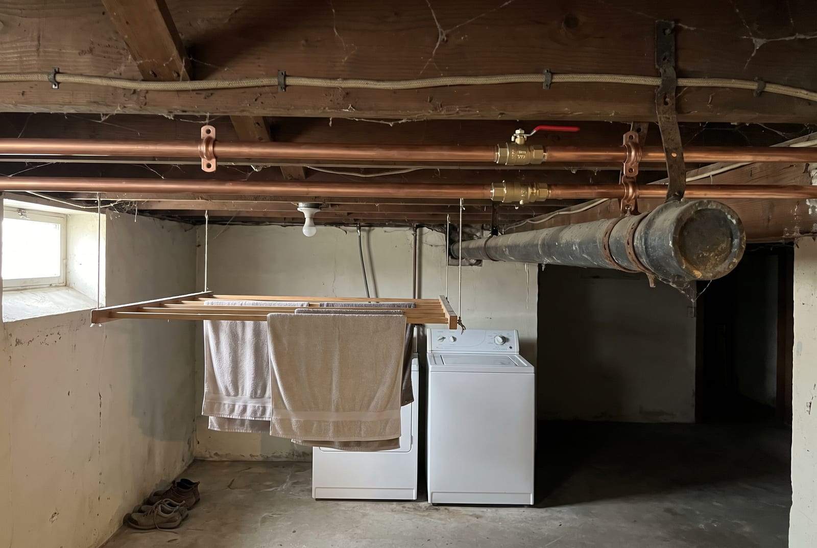 New copper water lines with ball valves run along the joists of an older basement